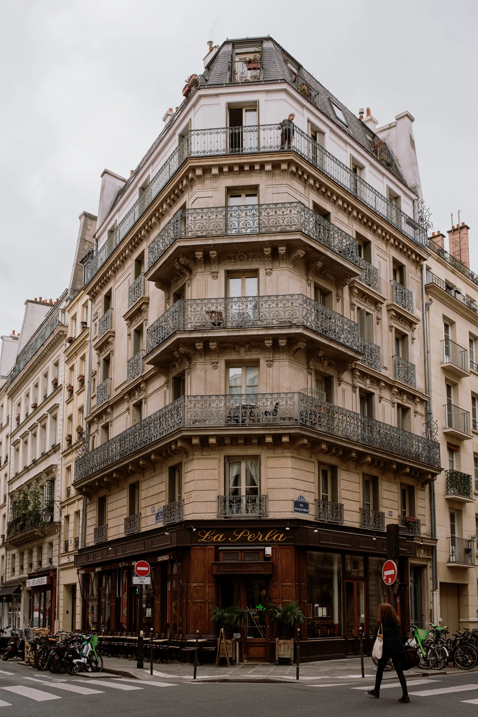 Haussmann-style corner building with curved iron balconies above a cafe, Paris