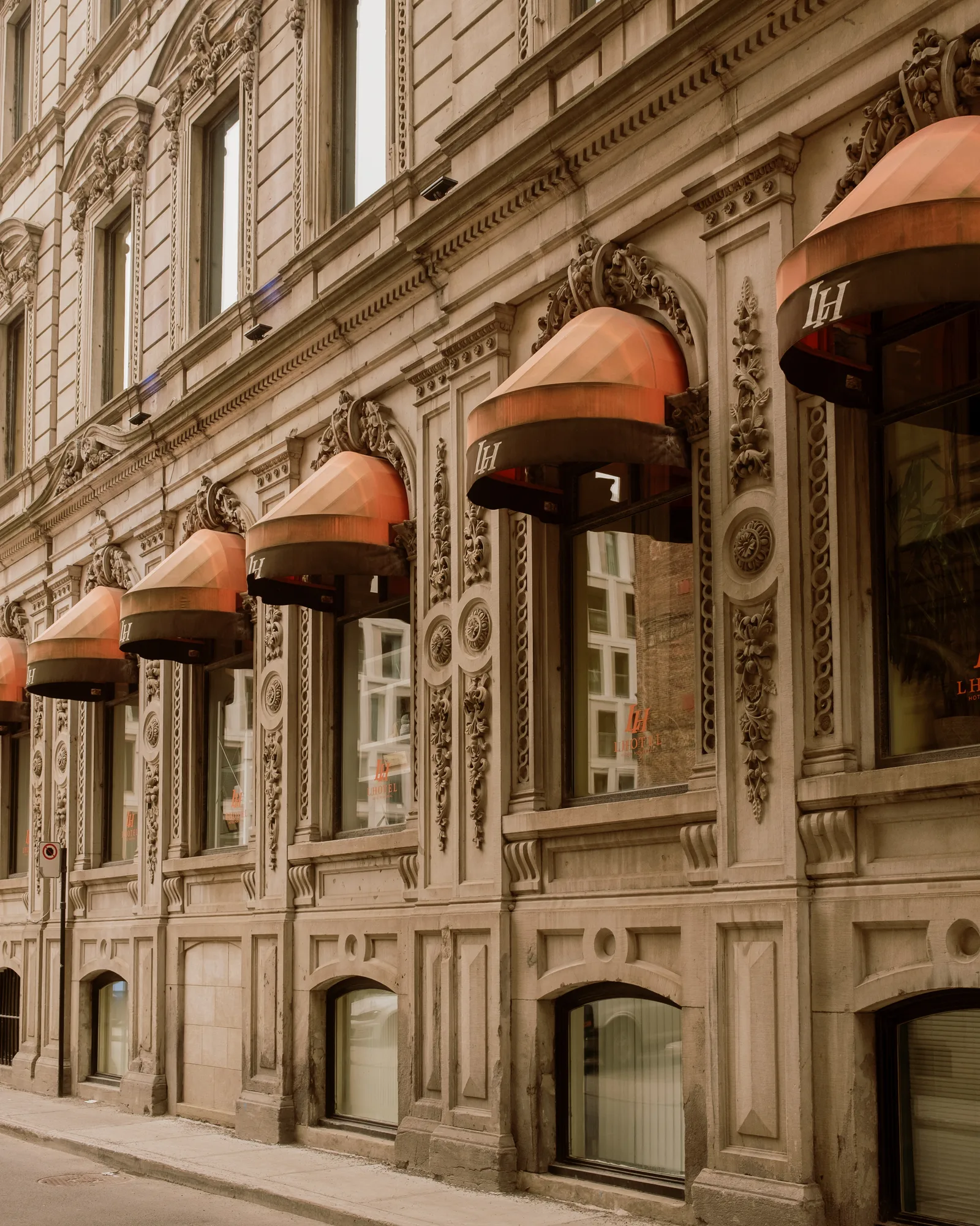 Ornate stone facade with orange-striped awnings above street-level windows, Montreal