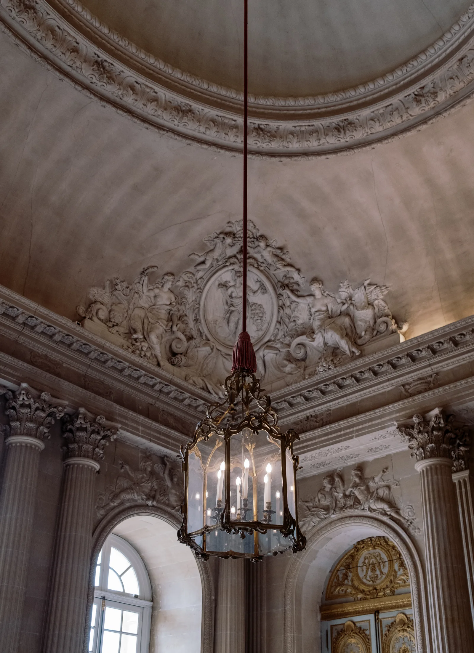 Domed hall with a hanging lantern, ornate plasterwork and an arched window, Paris