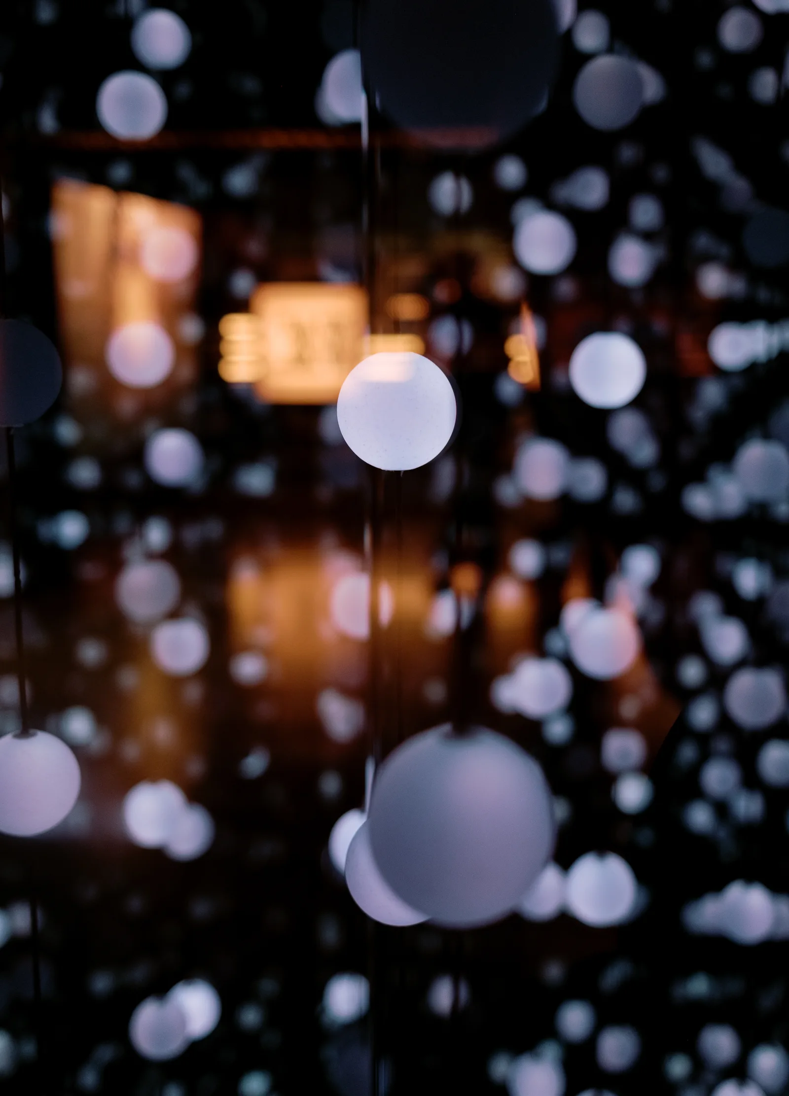 Blurred pale lights hanging in a dark Dublin interior, bokeh against warm glow