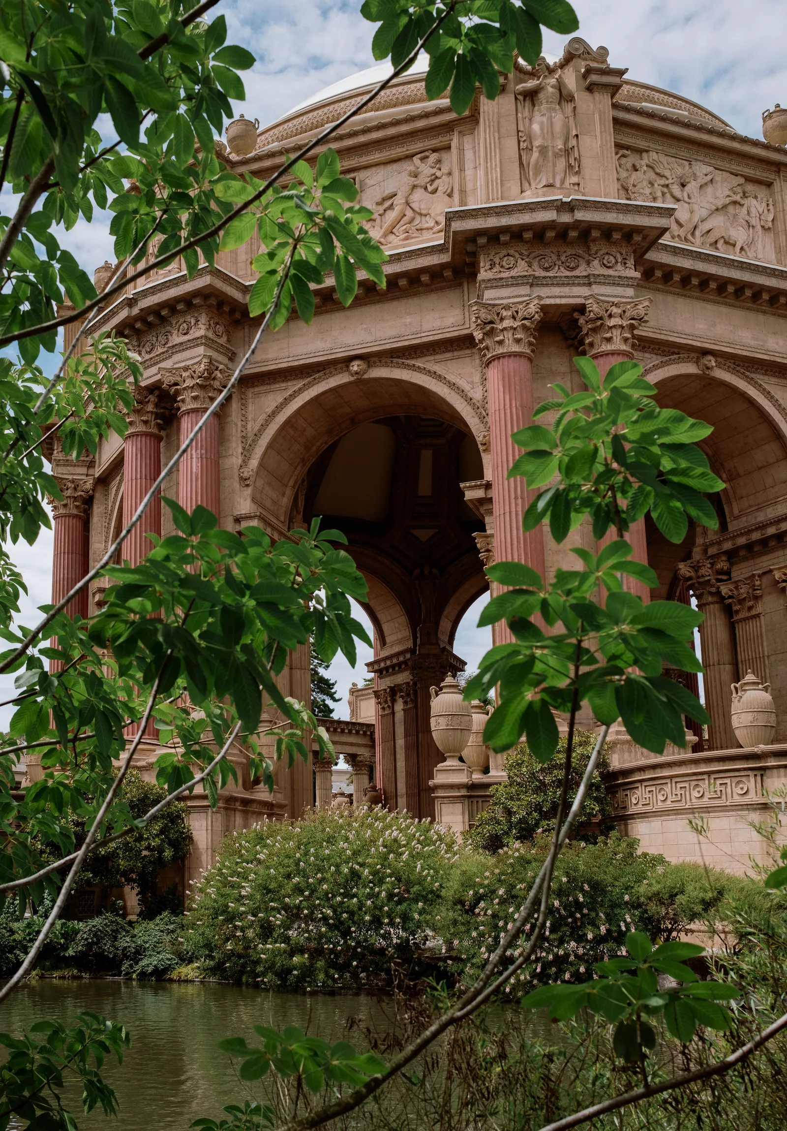 Palace of Fine Arts rotunda framed by leaves beside its lagoon, San Francisco