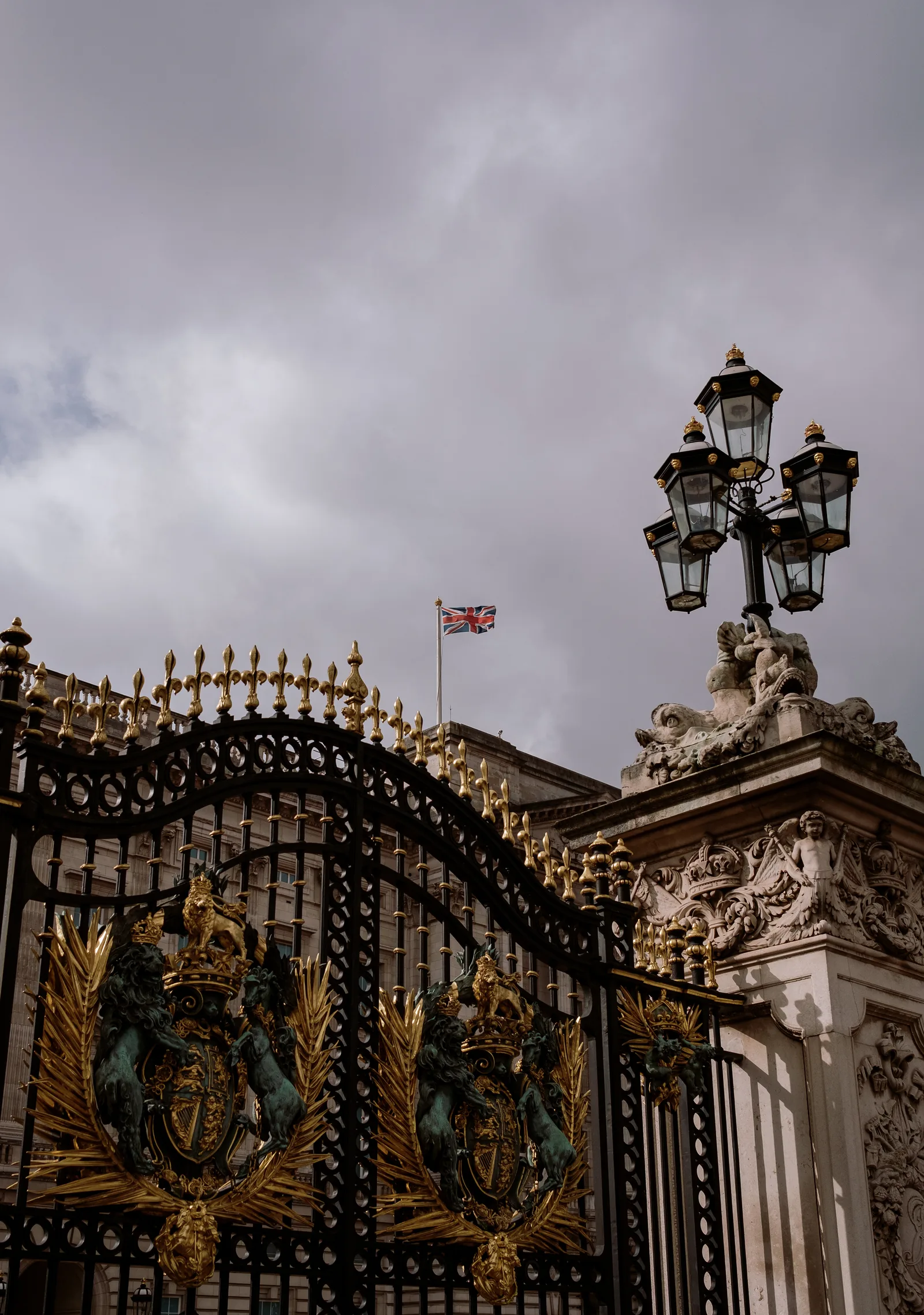 Gilded Buckingham Palace gate with a Union Jack and ornate lamp post, London