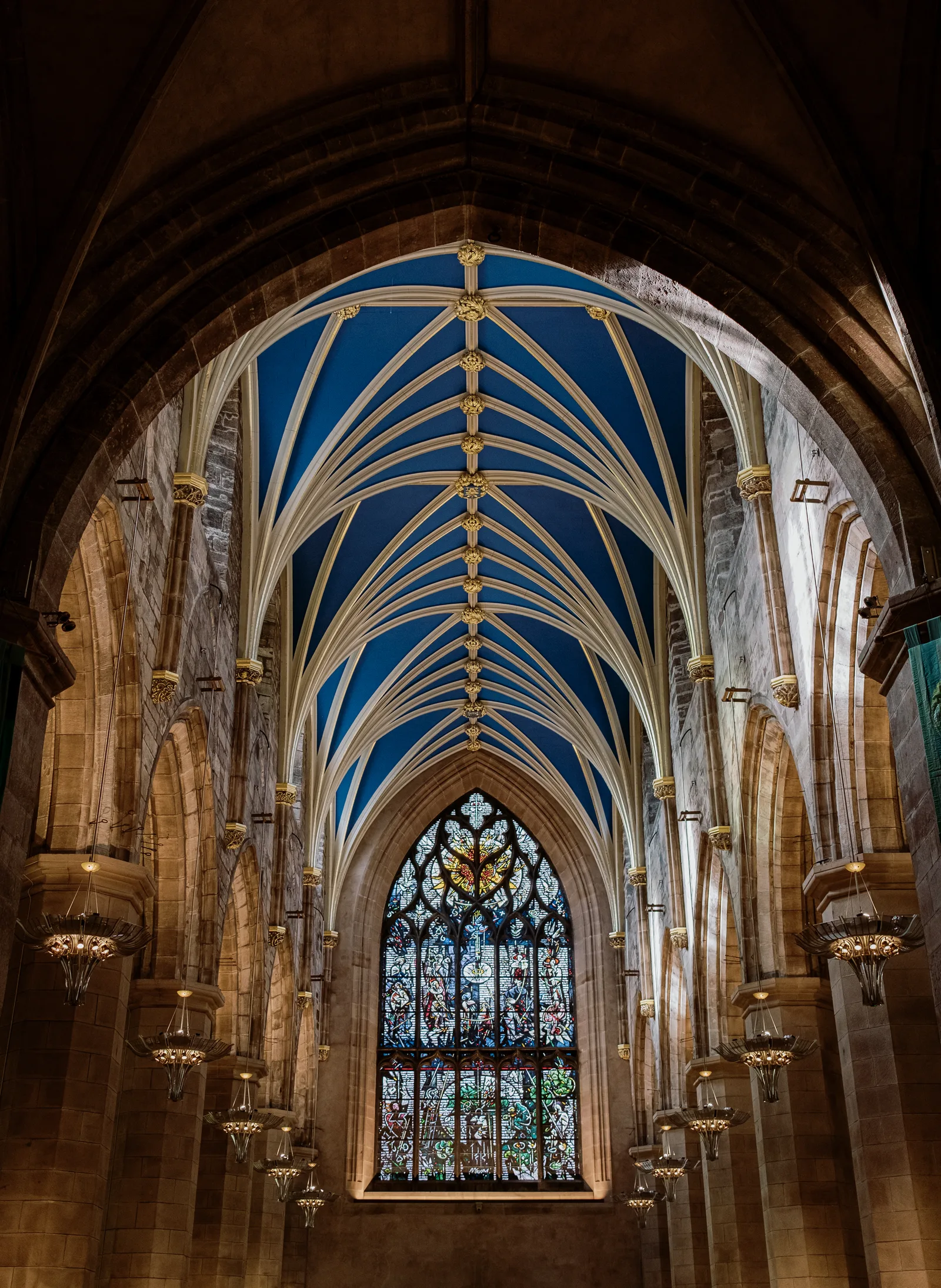 Gothic church nave in Edinburgh with a blue vaulted ceiling and a stained-glass window