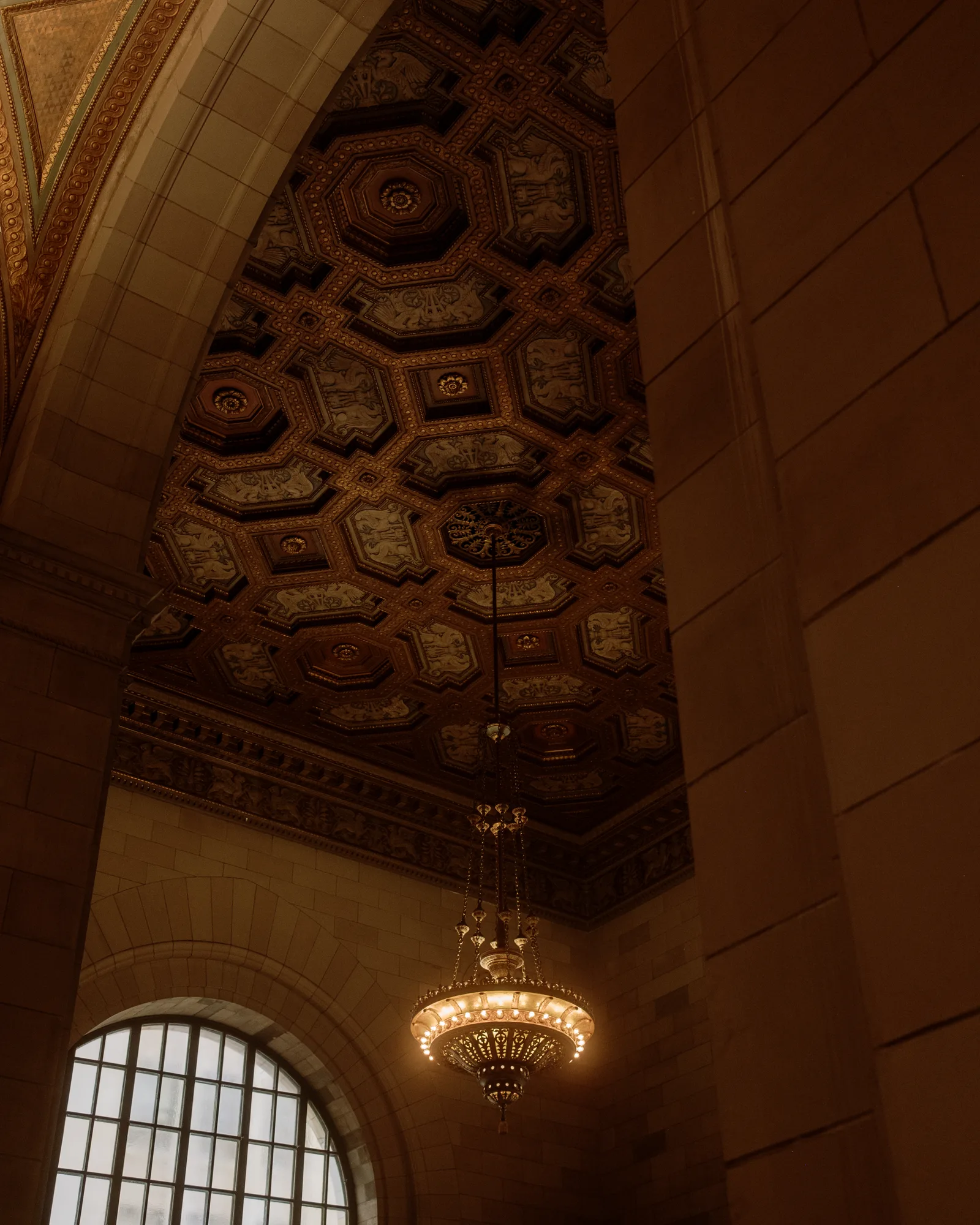 Coffered ceiling and hanging chandelier beneath a stone arch, Montreal