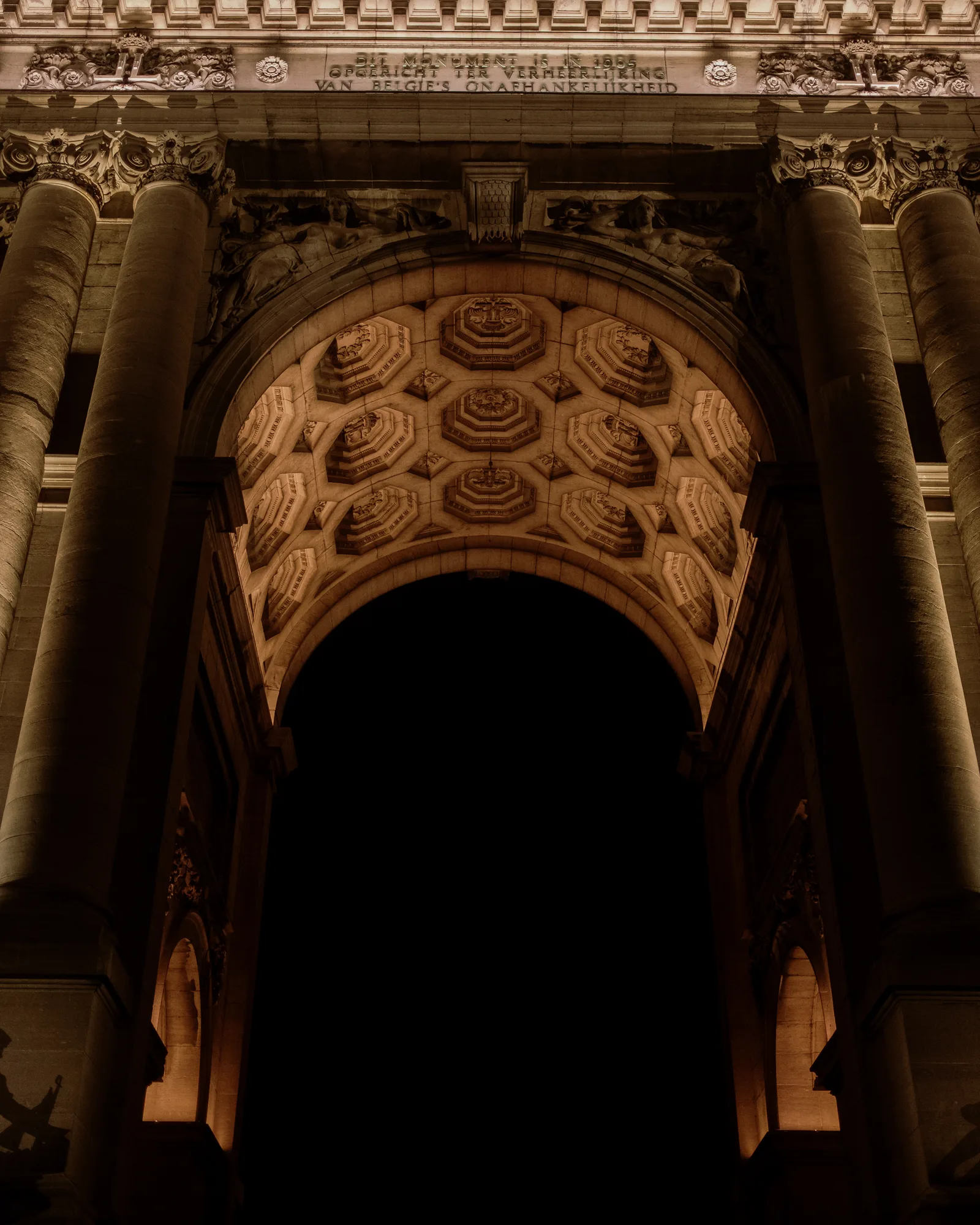 Coffered stone archway glowing above a dark passage, Brussels