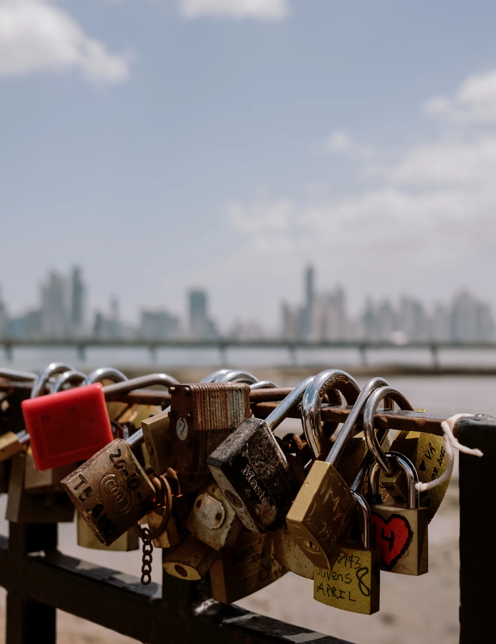 Padlocks clipped to a railing with the Panama City skyline blurred behind