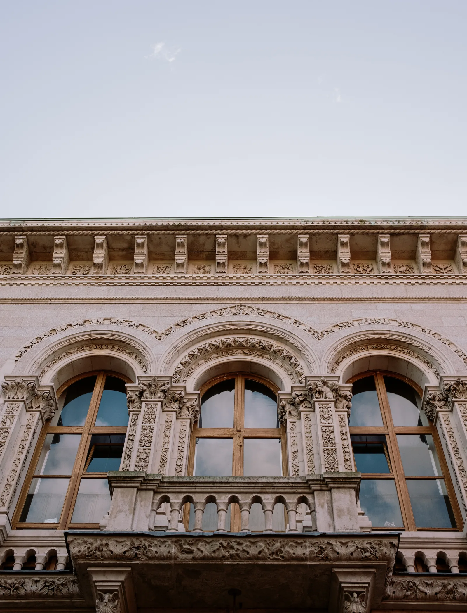 Carved stone facade with arched windows and a balcony under a pale sky, Dublin