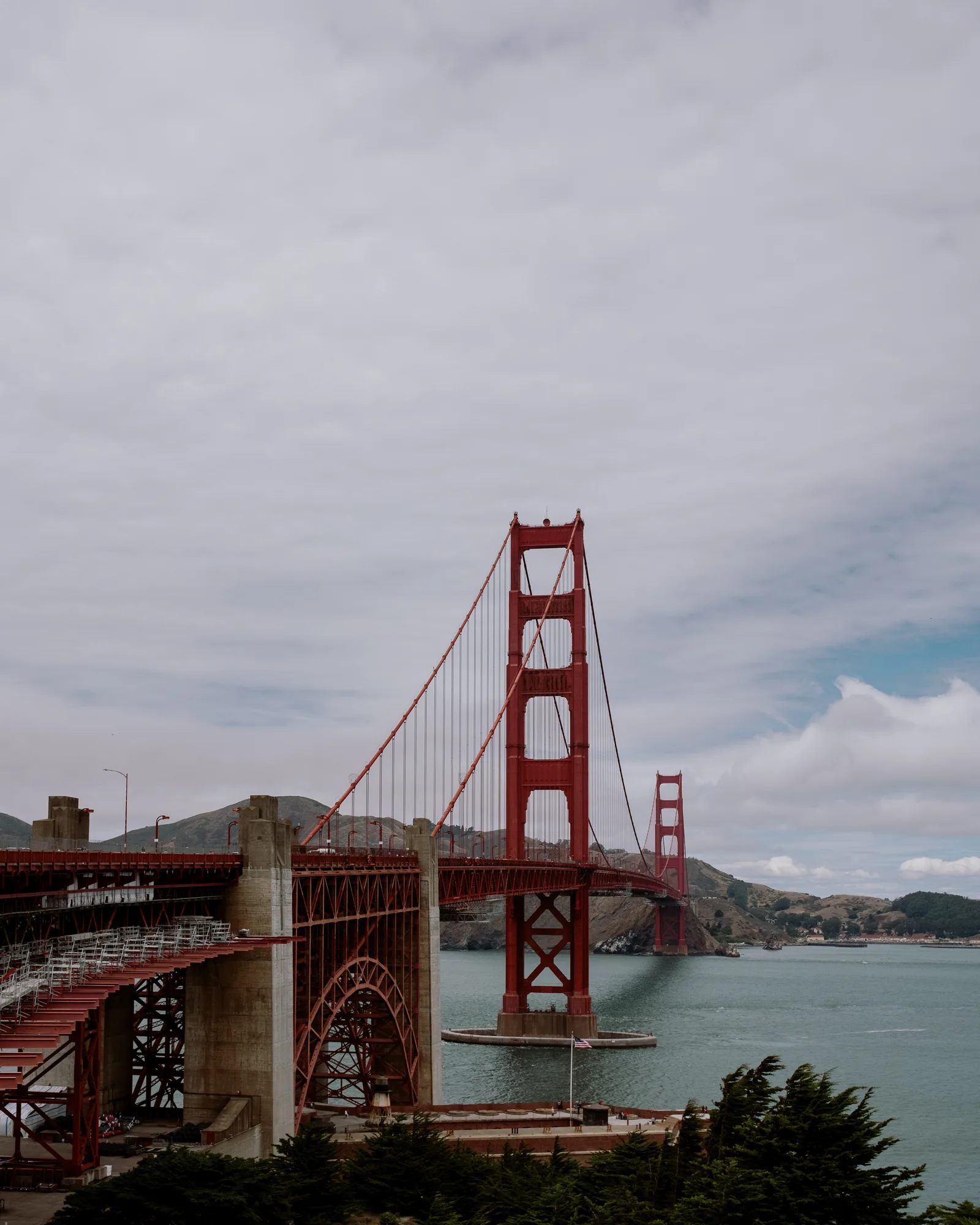 Golden Gate Bridge tower and roadway over the bay under a cloudy sky