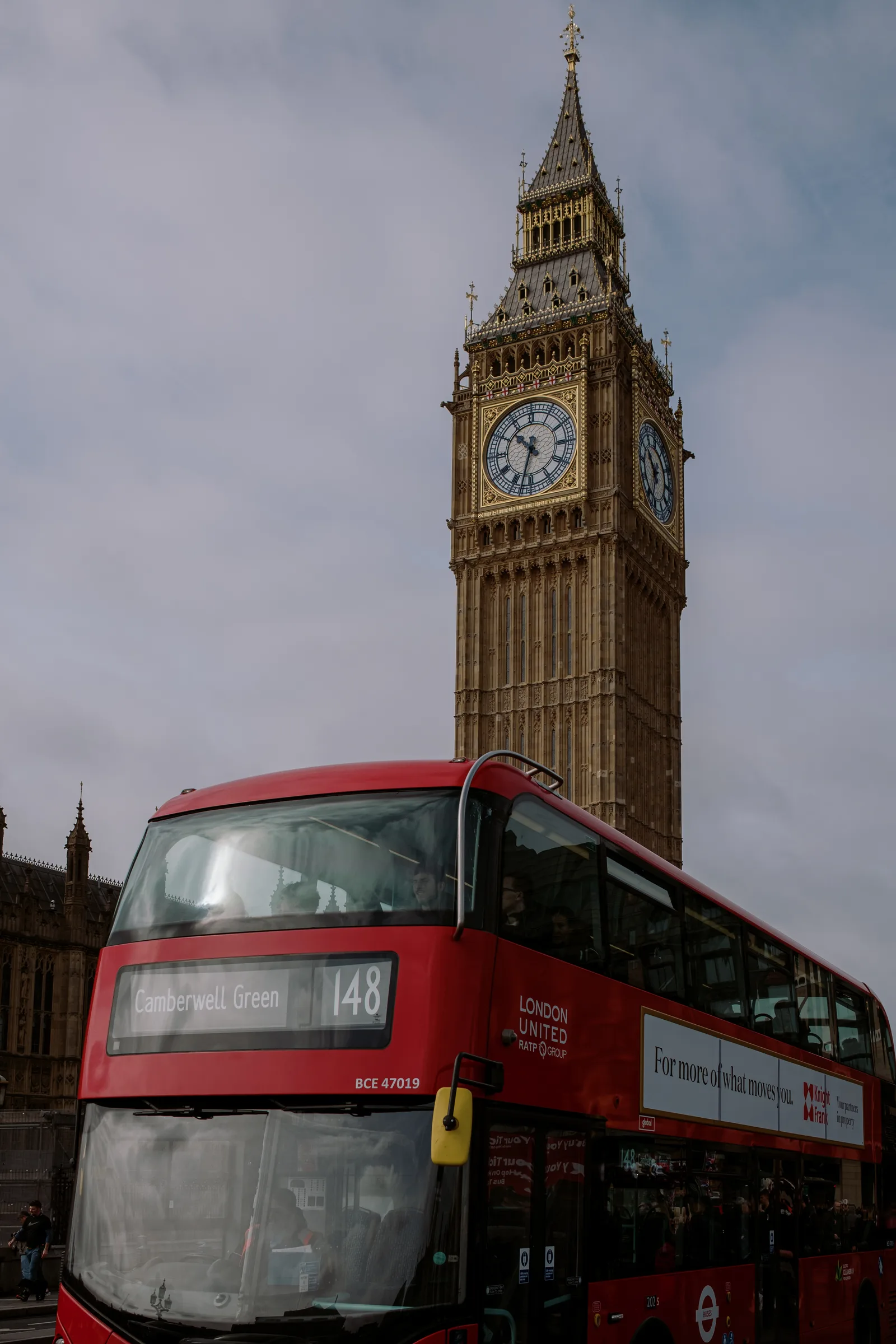 Red double-decker bus passing beneath Big Ben, London
