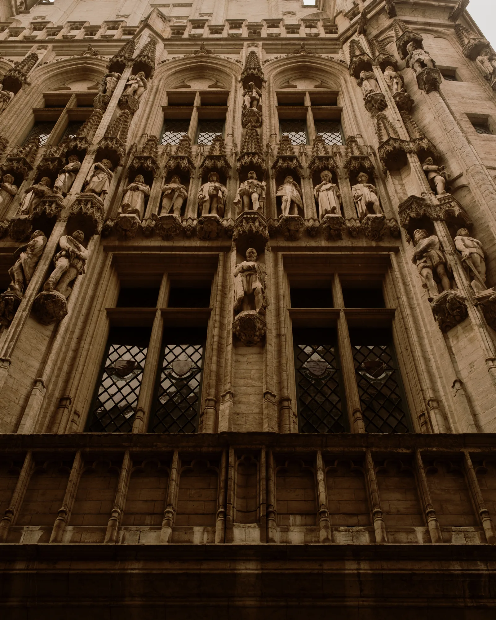 Ornate Gothic facade with rows of statues and diamond-paned windows, Brussels