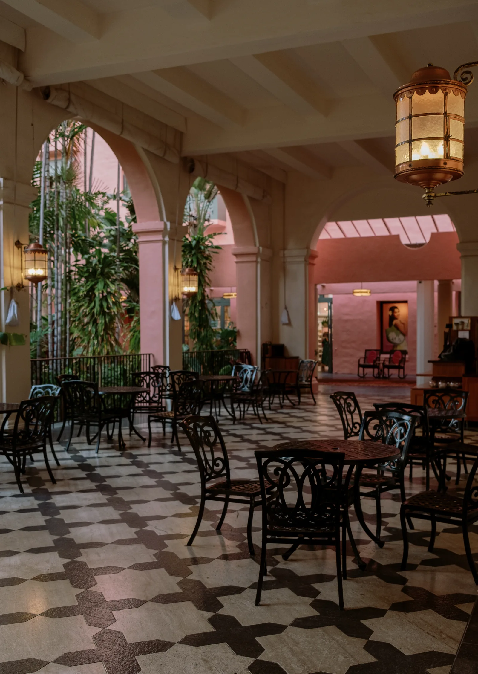 Open-air hotel lounge with checkered floor, bistro tables and pink arches, Waikiki