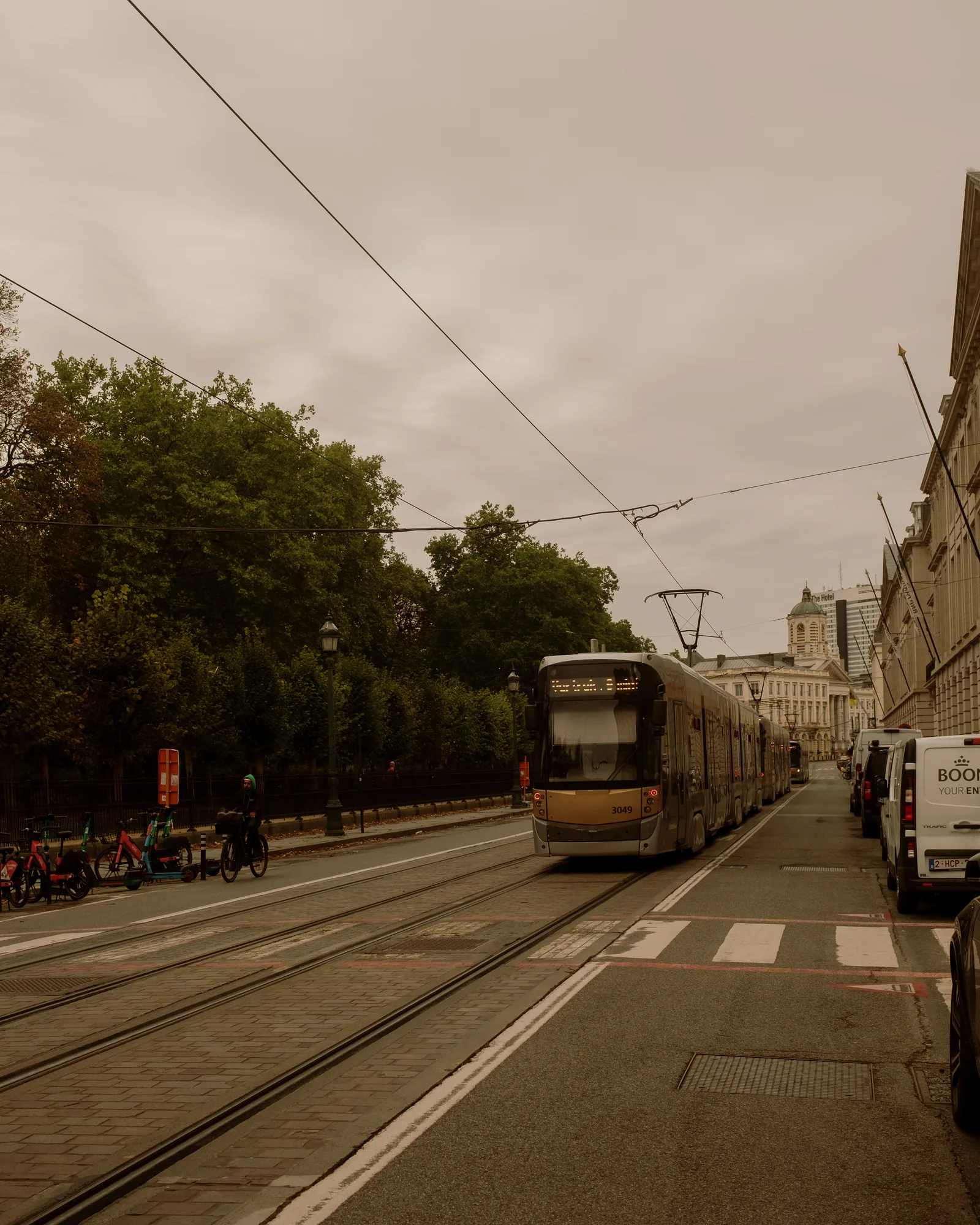 Tram on a tree-lined boulevard under an overcast sky, Brussels
