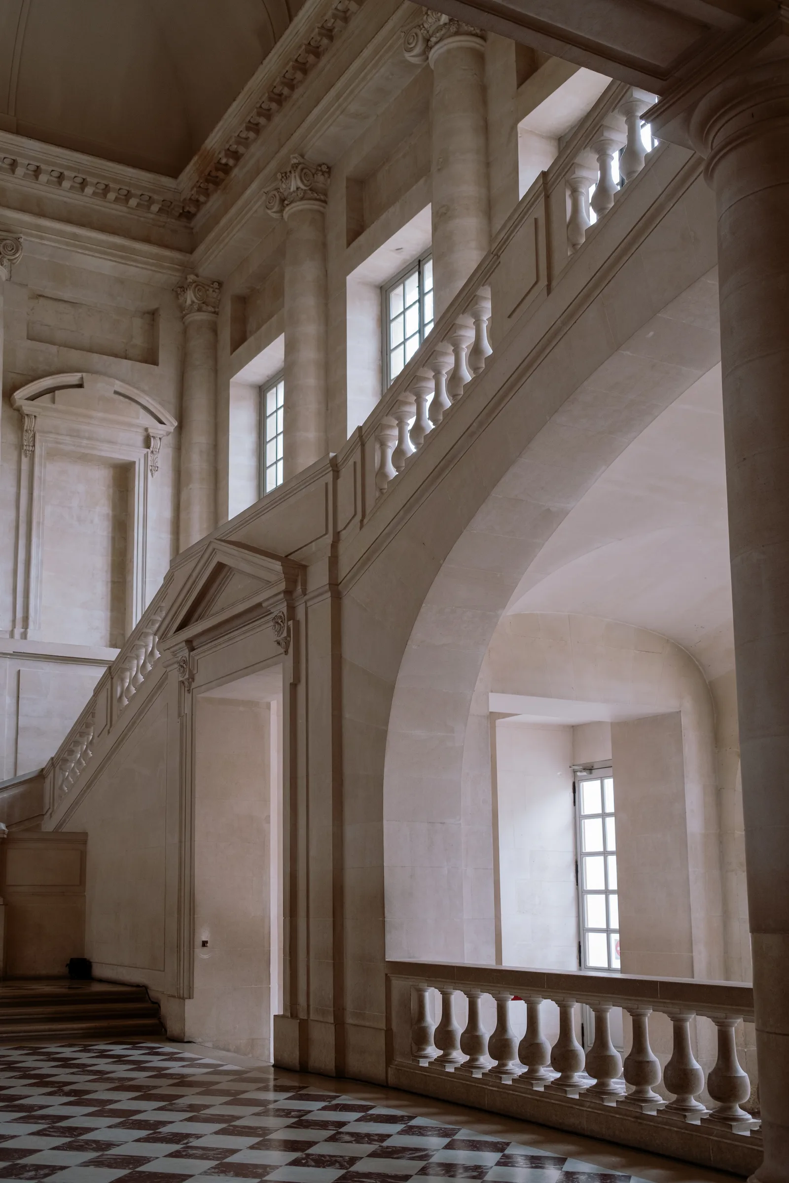 Stone staircase with balustrade and checkered floor in a palace stairwell, Paris