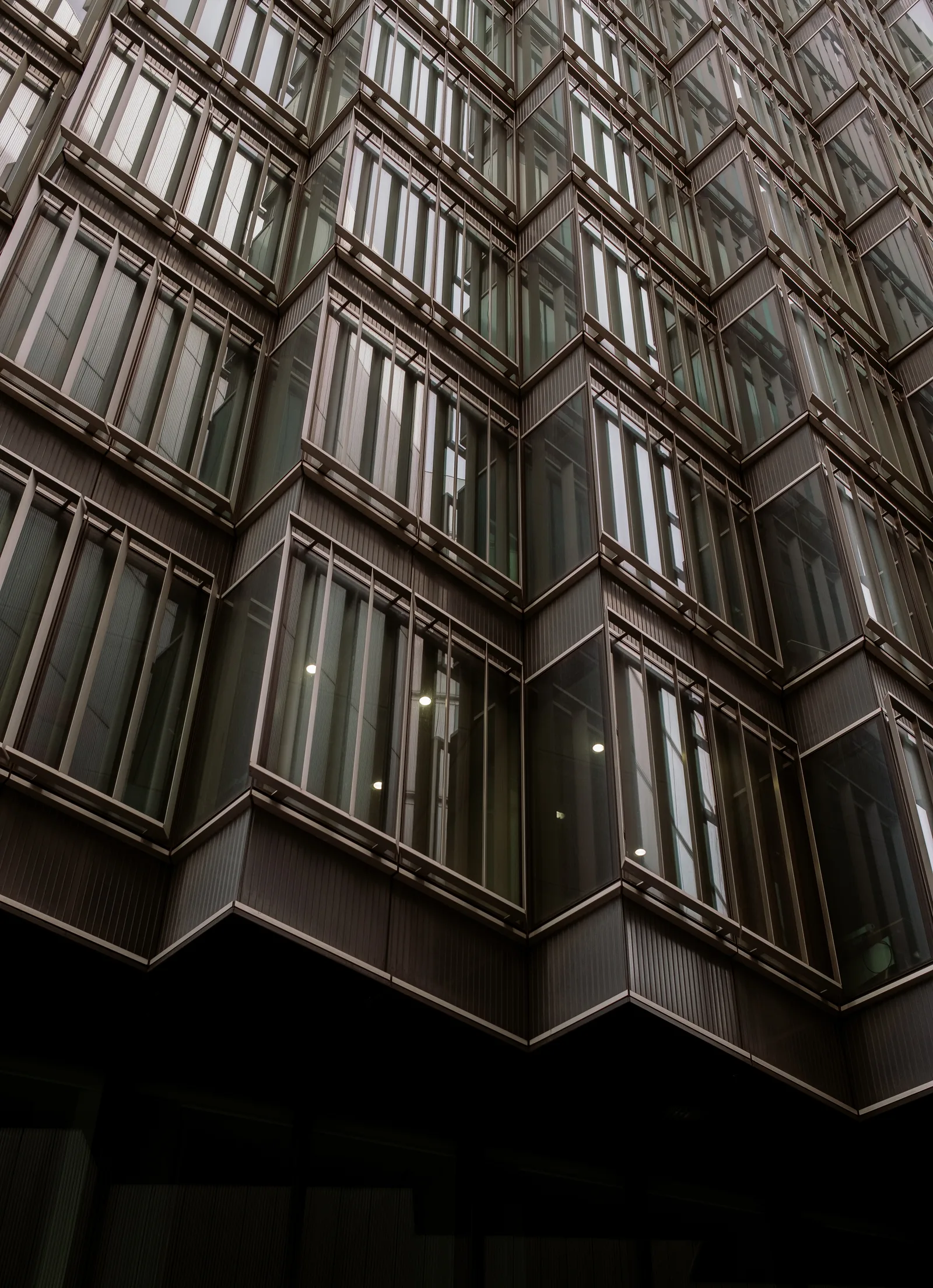 Angular dark glass building facade seen from below, London