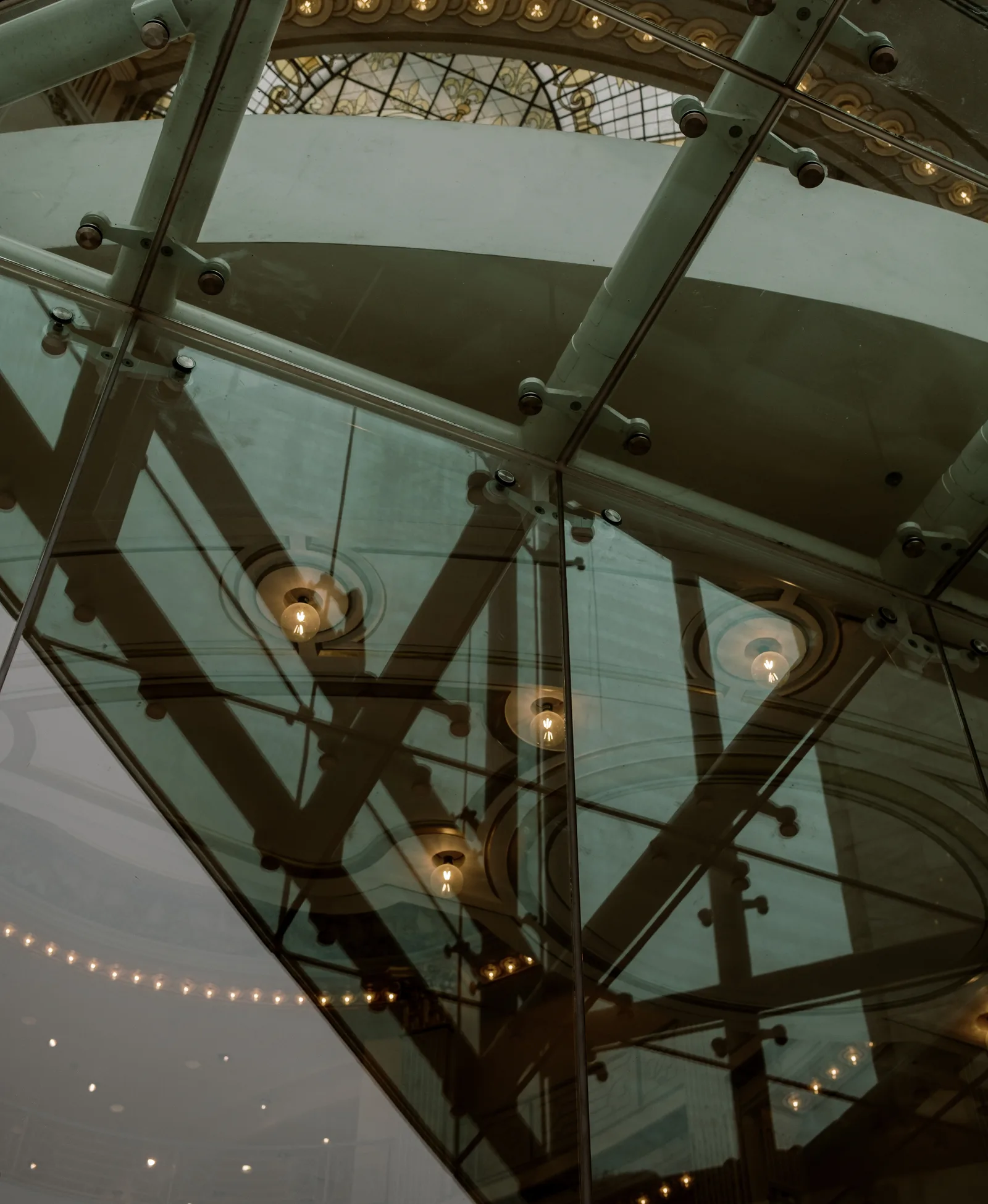 Looking up at a glass floor and stained-glass dome with string lights, San Francisco