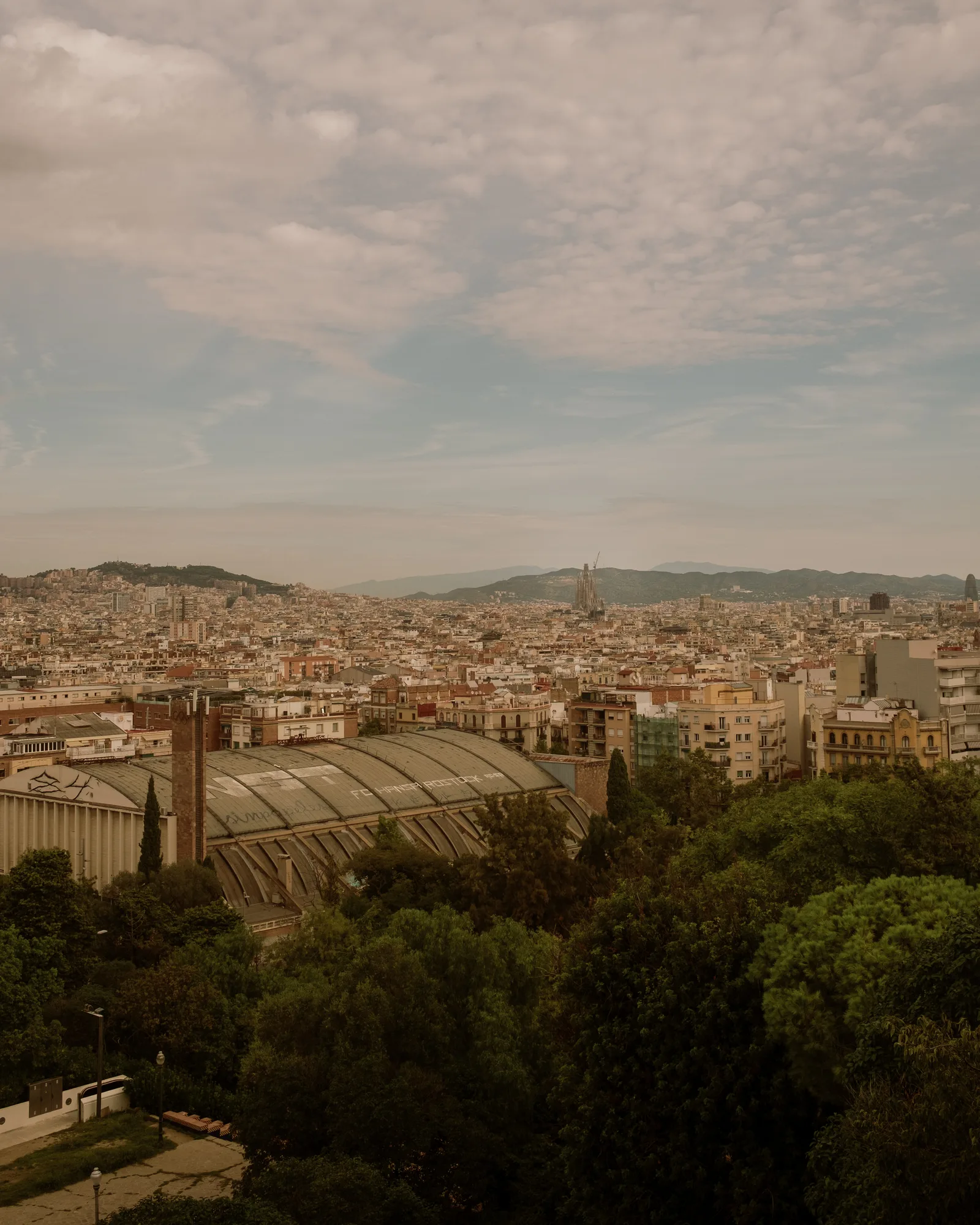 Barcelona cityscape with a curved glass roof in the foreground and hills on the horizon