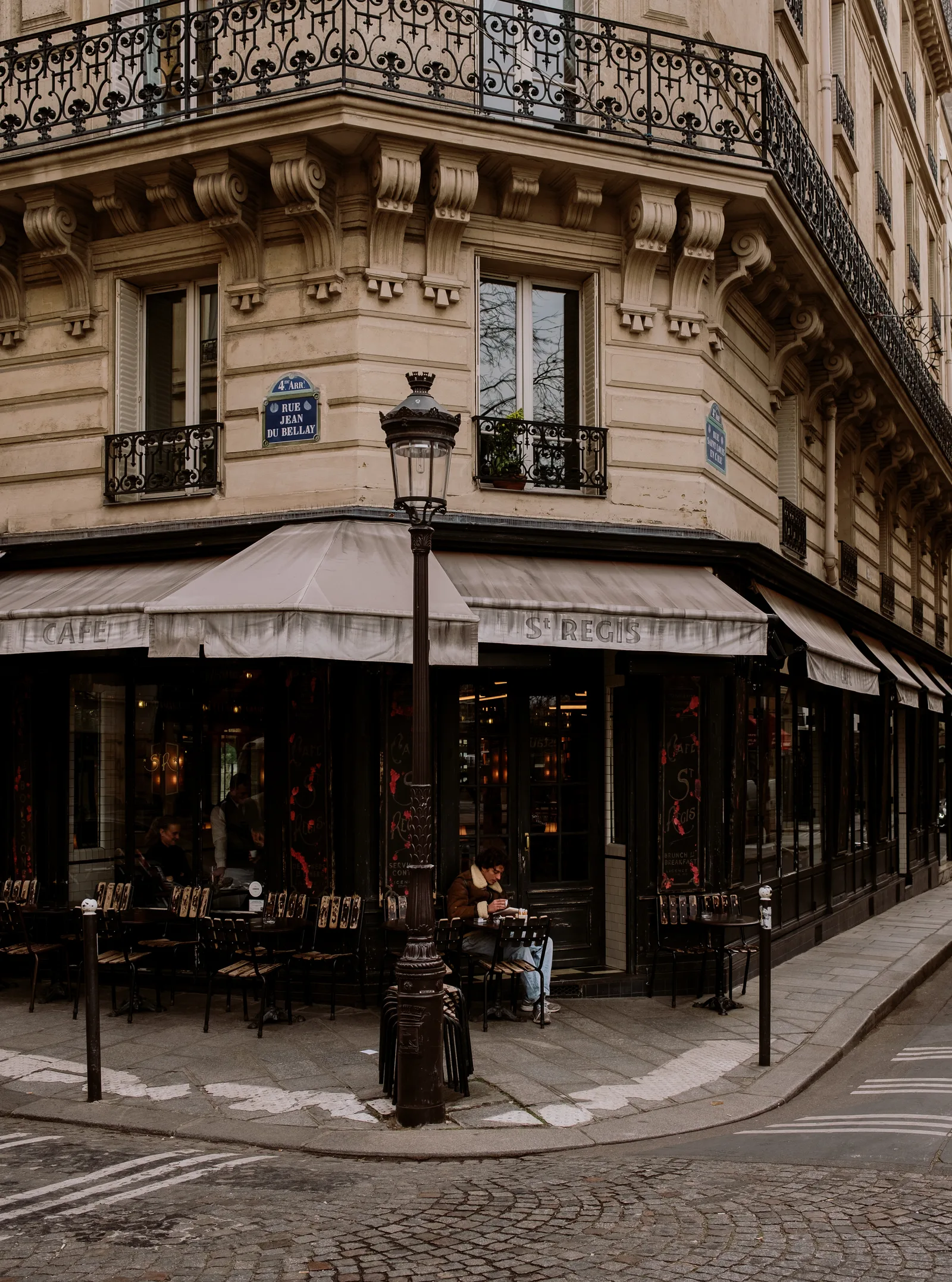 Paris corner cafe with a street lamp, awning and iron balconies above