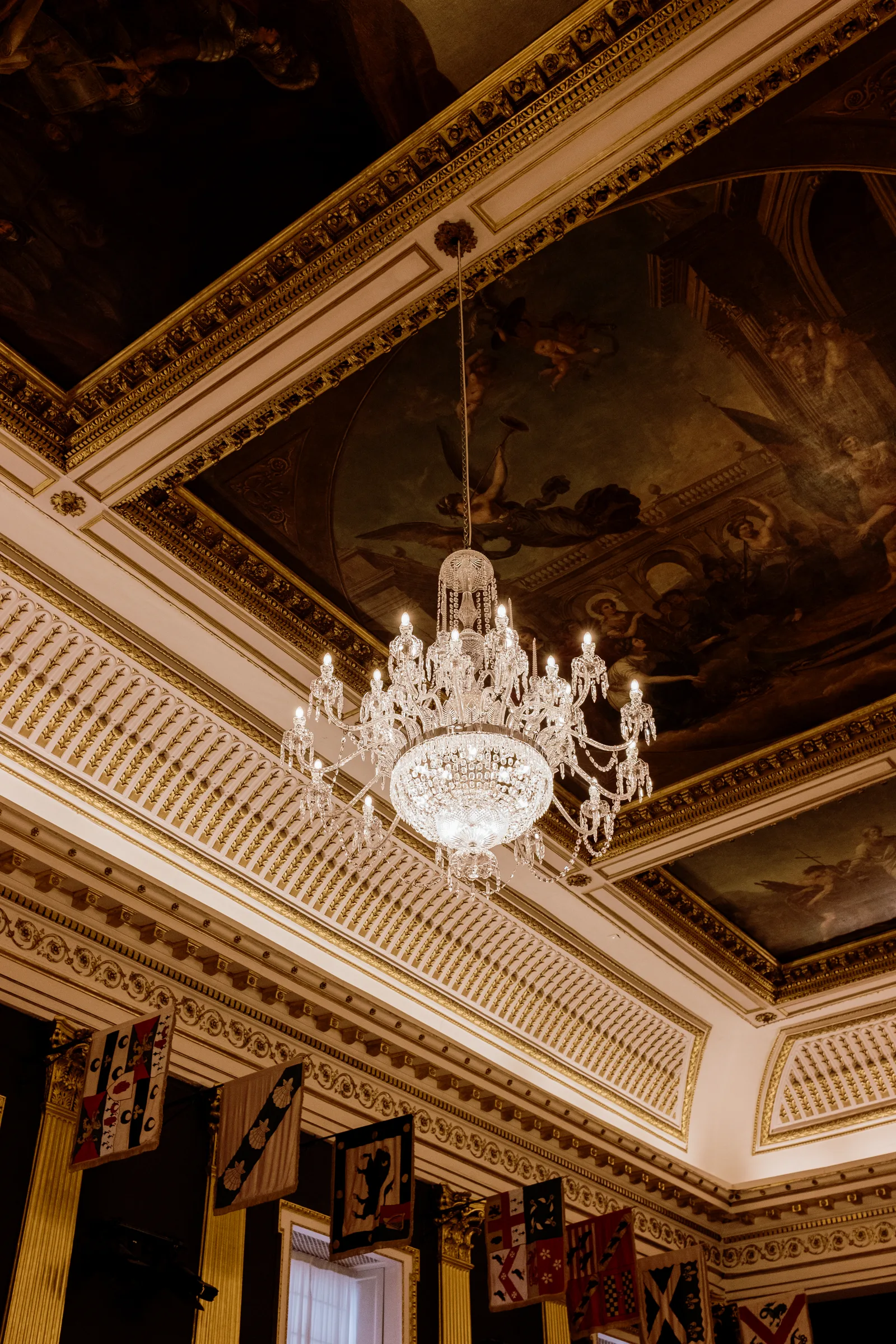 Gilded ceiling with a crystal chandelier and hanging banners in a Dublin hall