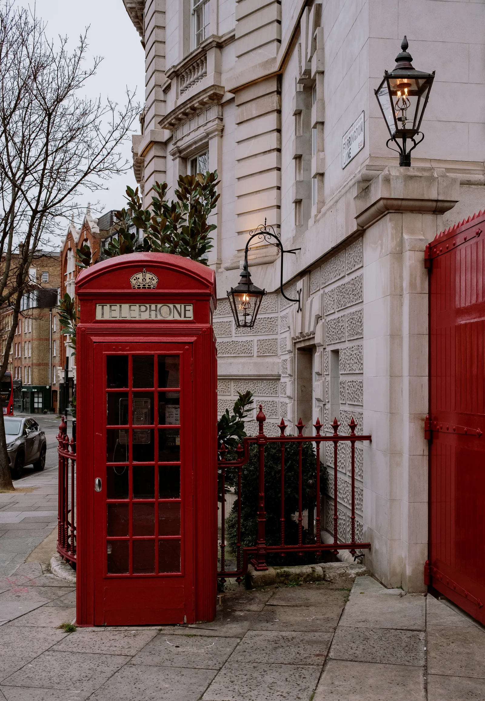 Red telephone box beside a lamp and a pale stone building, London