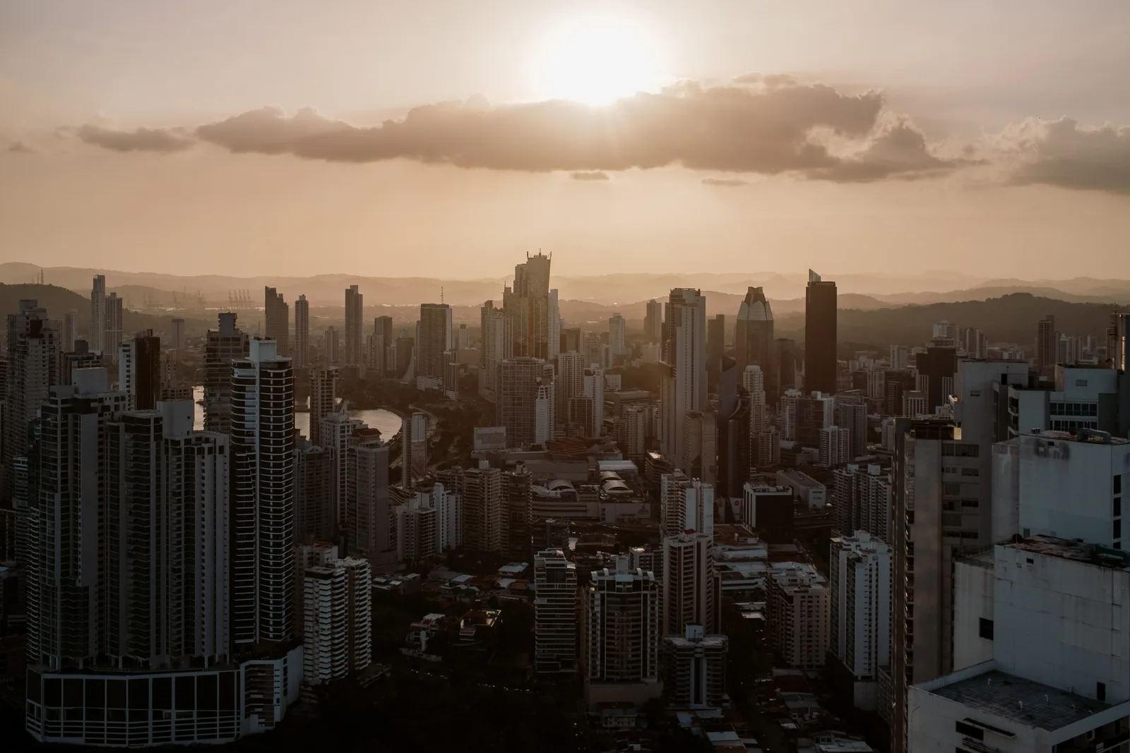 Panama City skyline at sunset from above, sun low behind clouds