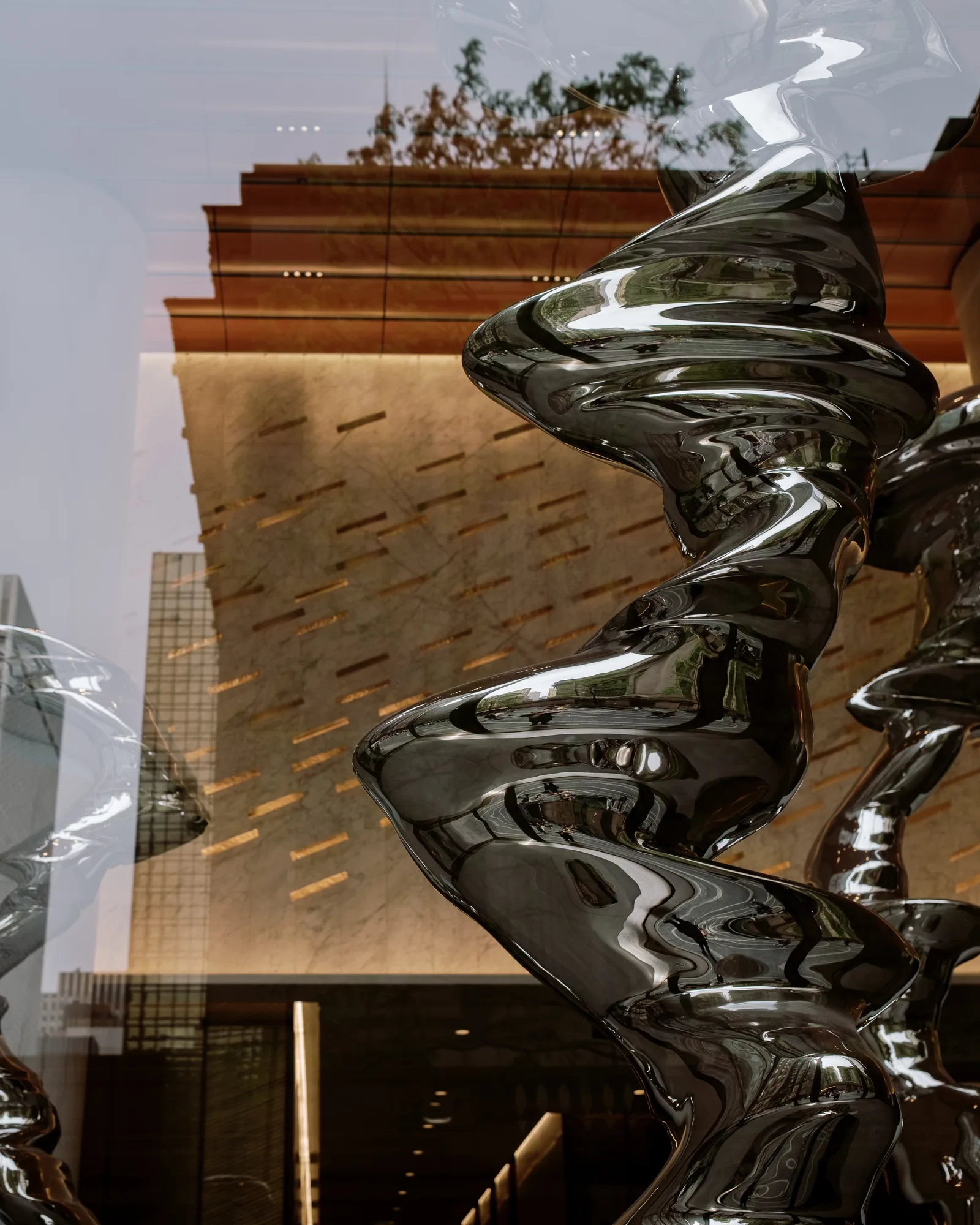 Twisting chrome sculpture beside a copper-paneled wall, New York