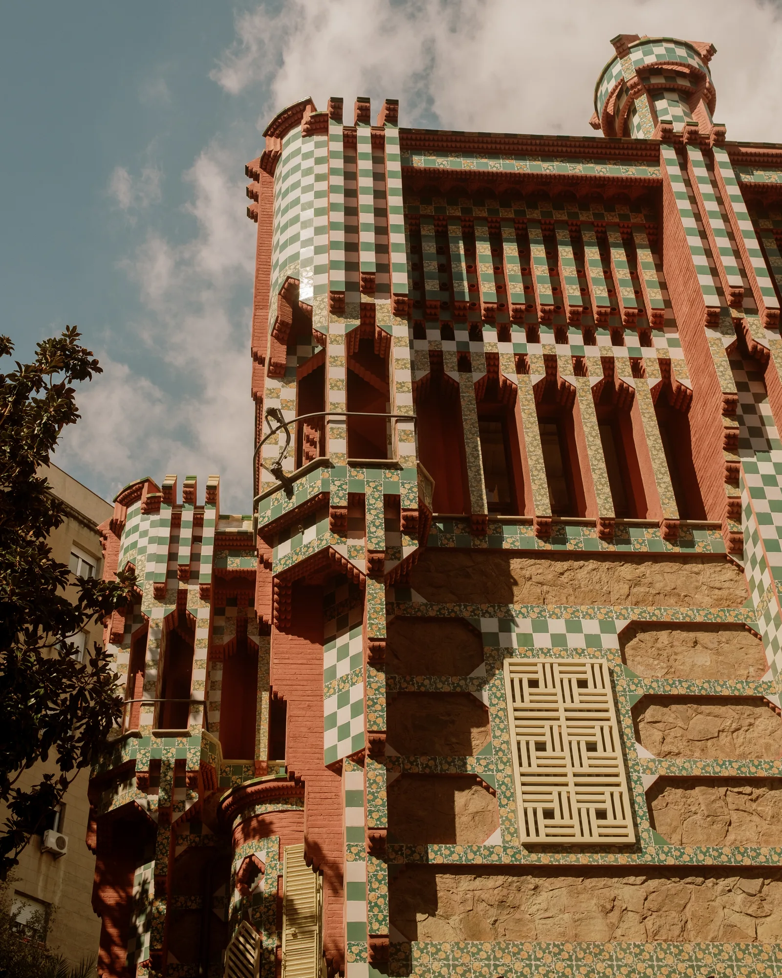 Casa Vicens in Barcelona, a tower of red brick and green-and-white tile against blue sky