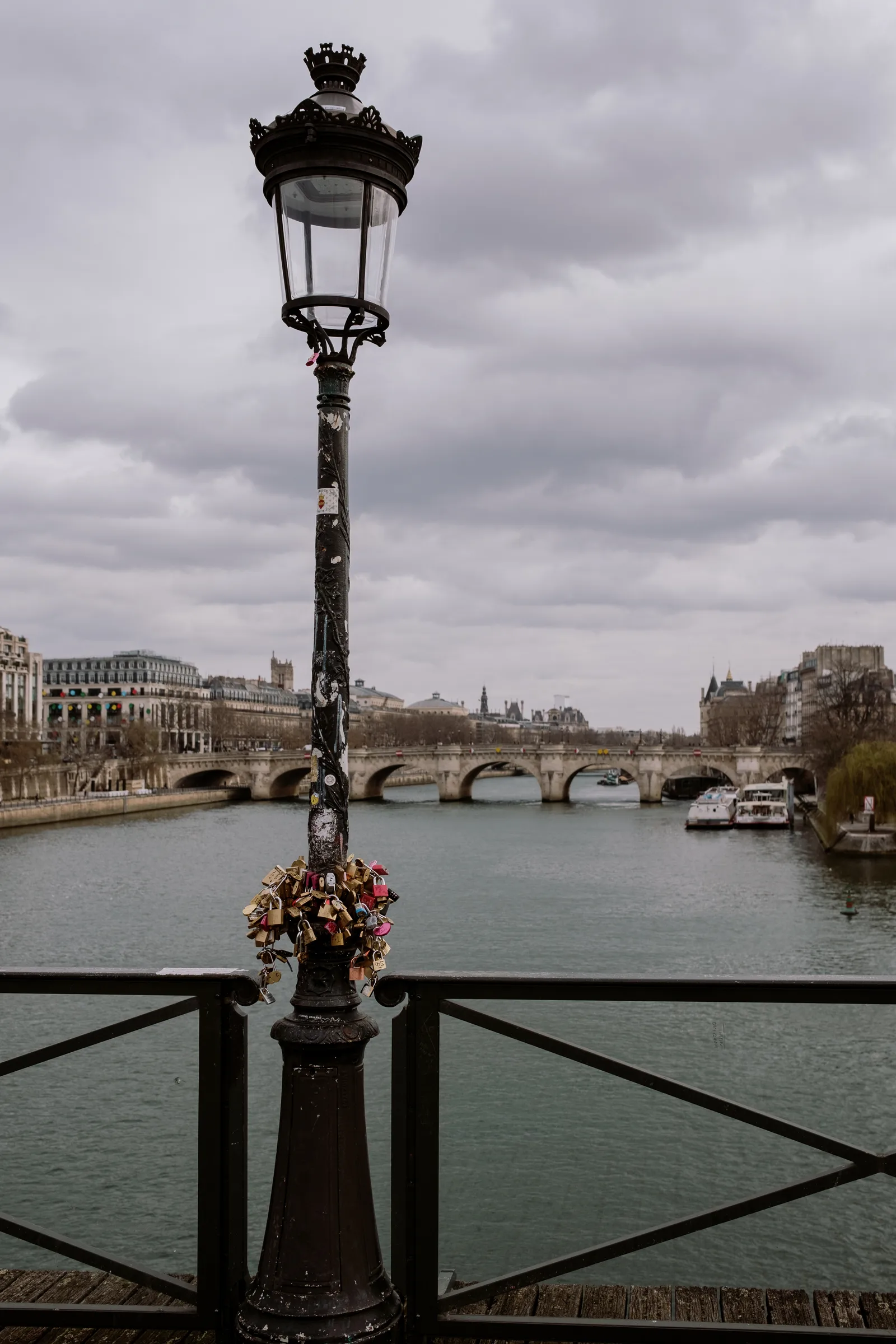 Street lamp and a bridge over the Seine under heavy clouds, Paris