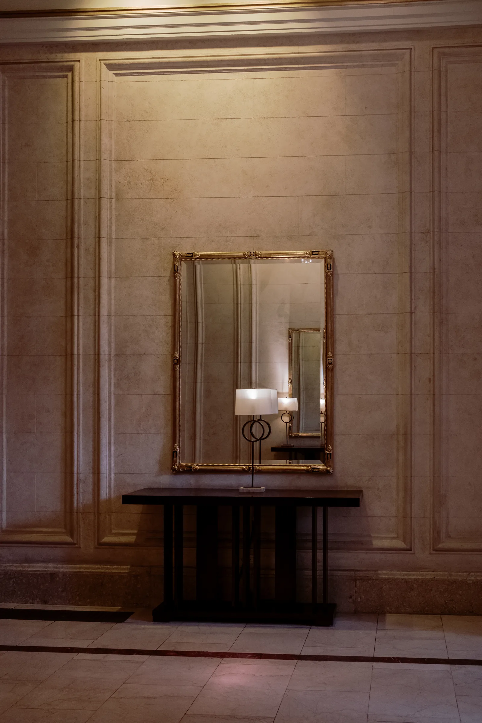 Gilt mirror above a dark console with a lamp on a paneled hotel wall, San Francisco