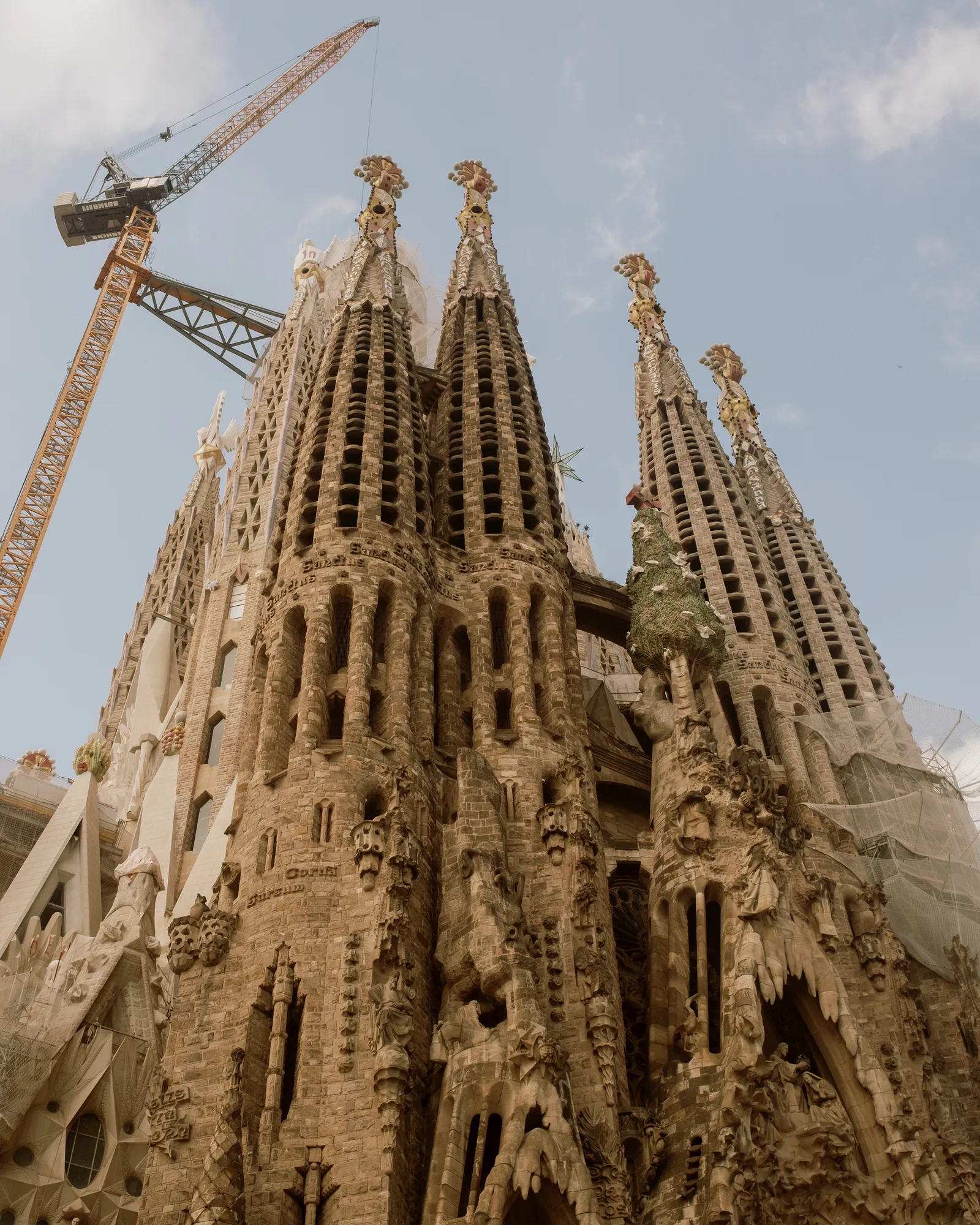 Sagrada Família towers against blue sky with a construction crane, Barcelona