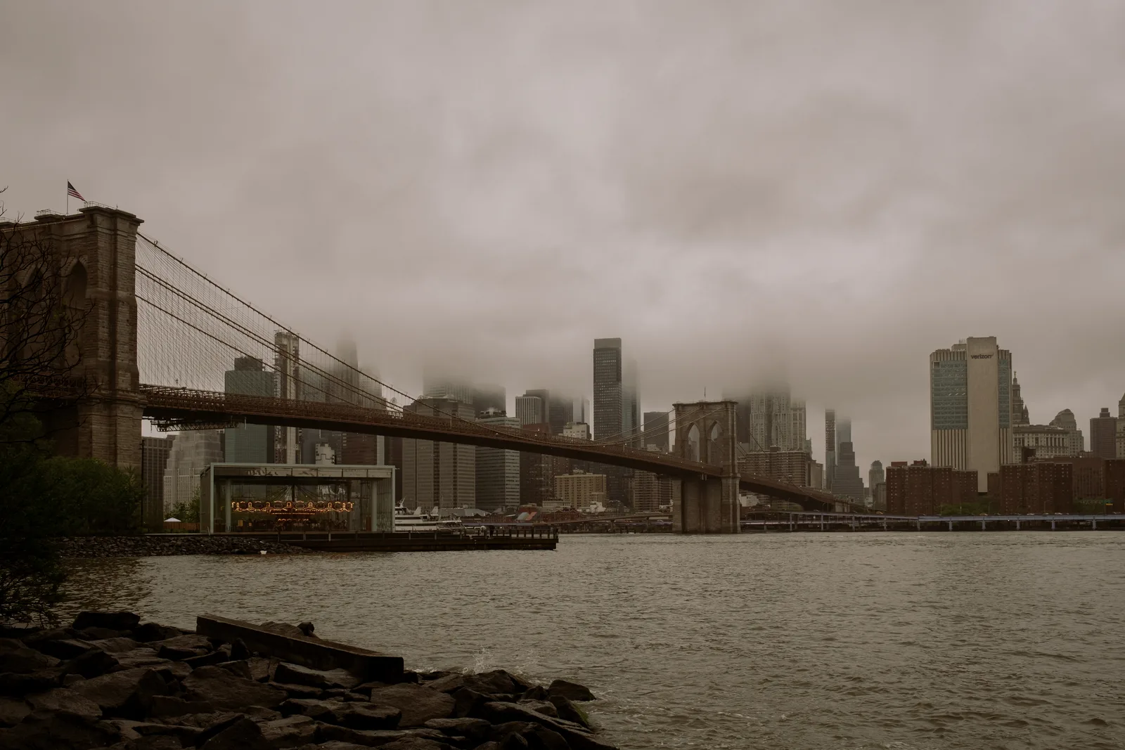 Brooklyn Bridge and the Manhattan skyline under low cloud across the East River