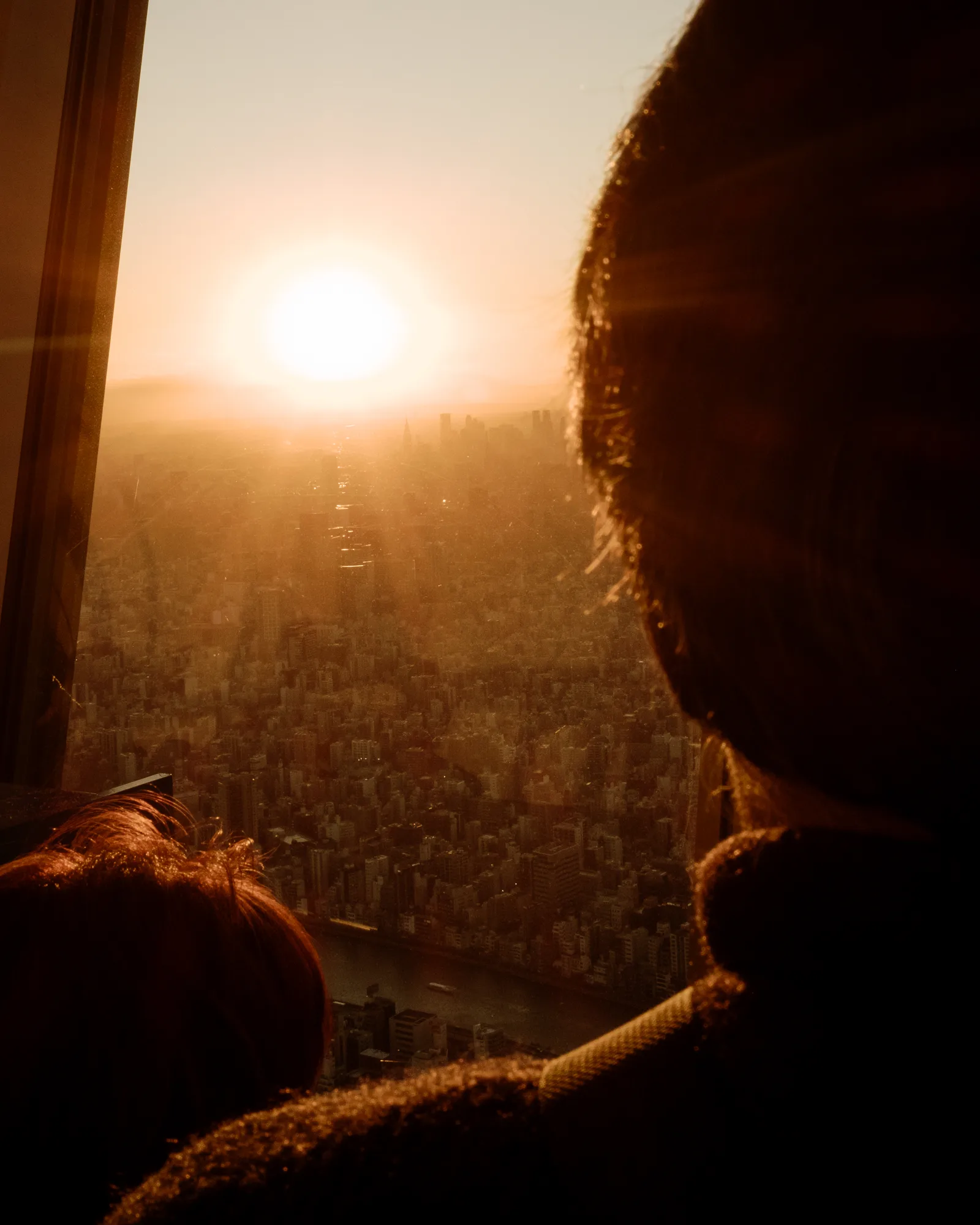 Sun setting over Tokyo, two people in silhouette in the foreground