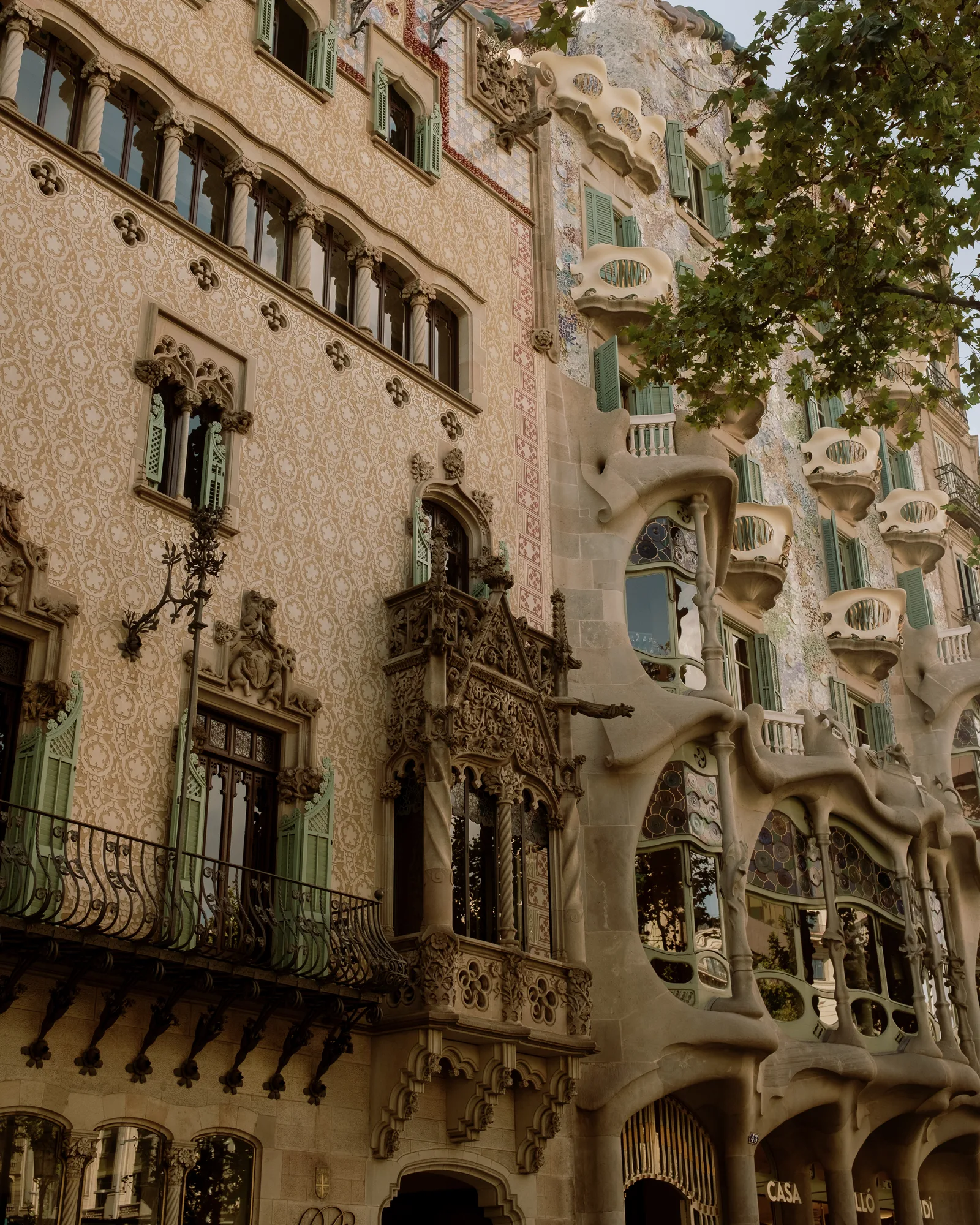 Two ornate modernista facades side by side, one tiled and one wavy-stone, Barcelona