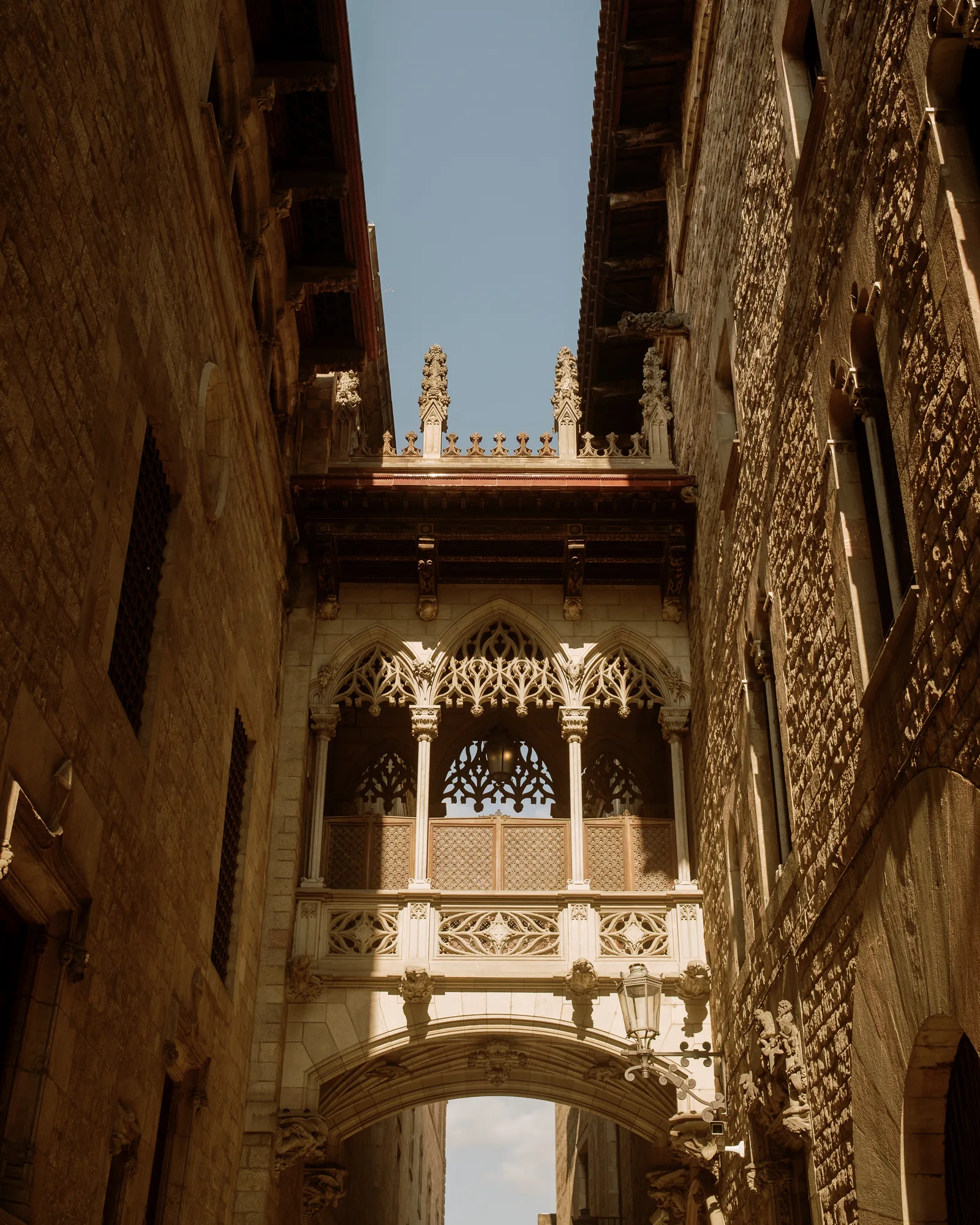 Gothic covered bridge between two stone buildings in Barcelona's old town, blue sky above
