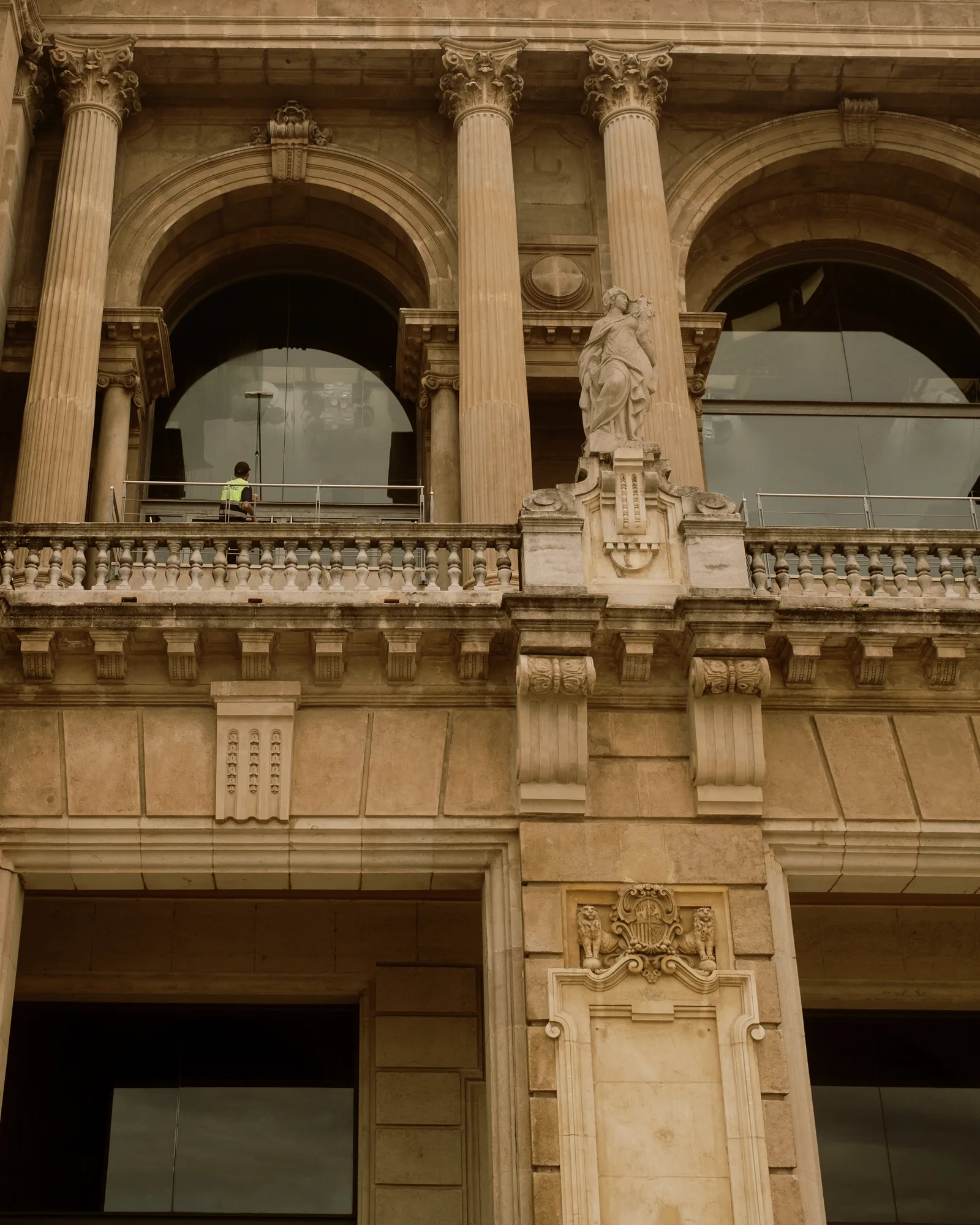 Barcelona stone building front with columns, arched windows and a statue above the balcony