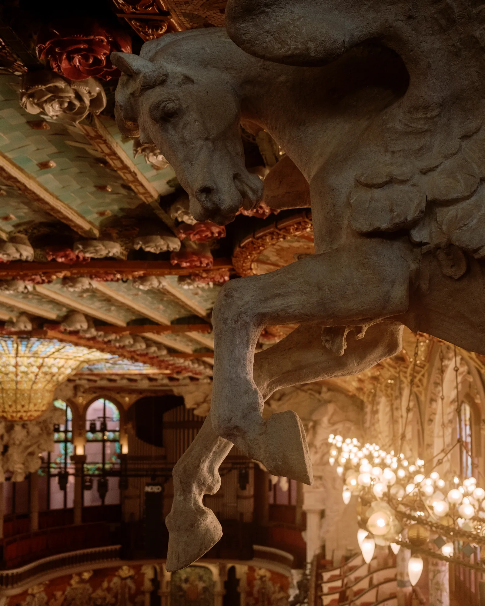Sculpted winged horse in an ornate tiled hall lit by chandeliers, Barcelona