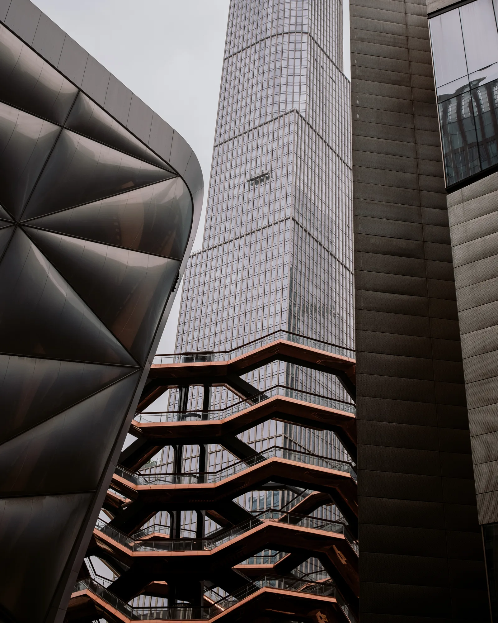 Hudson Yards' Vessel staircase and a curved copper wall beside a glass tower, New York