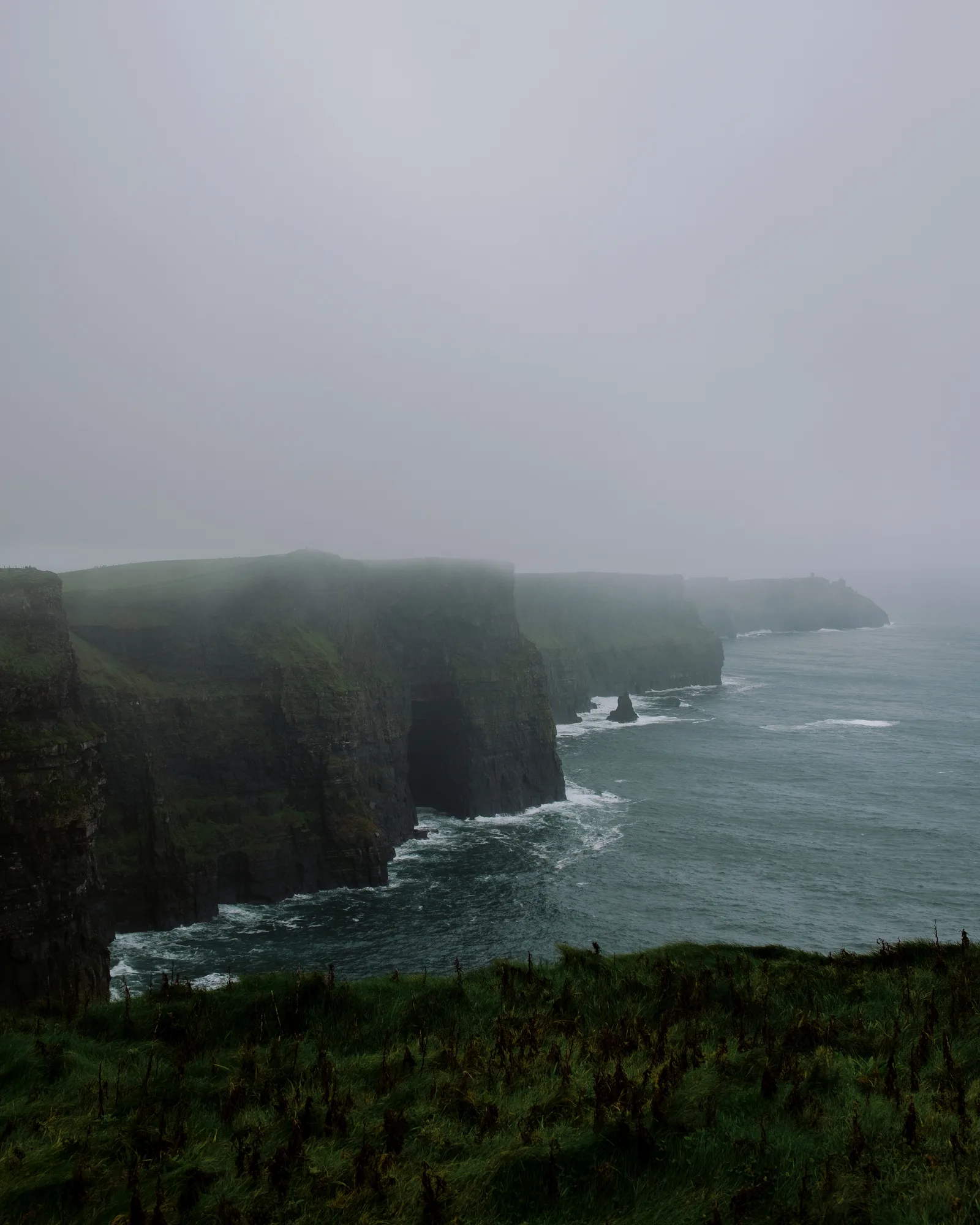 Cliffs of Moher fading into fog above a dark Atlantic sea, Ireland