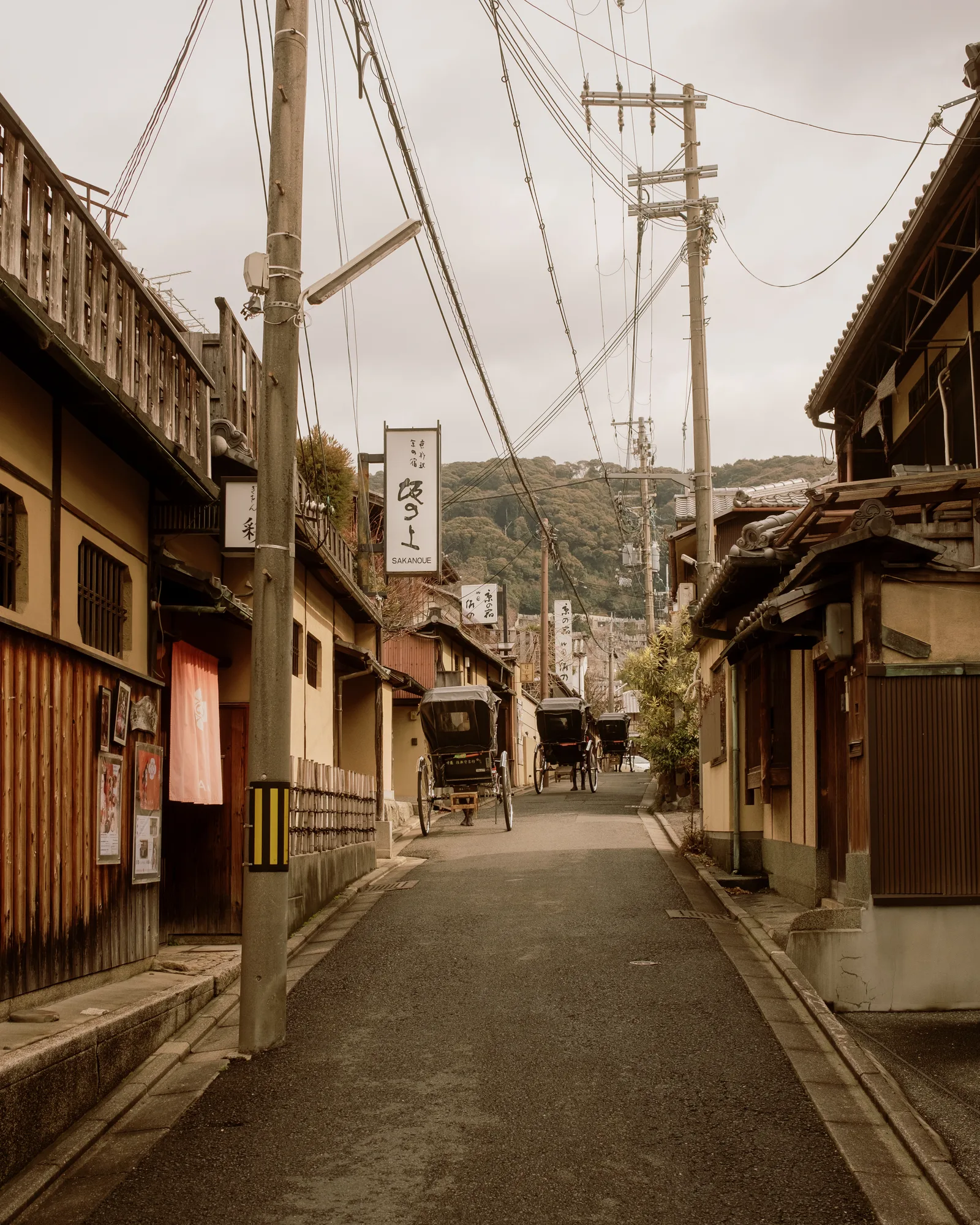 Kyoto street with wooden buildings, utility poles and a rickshaw in the distance